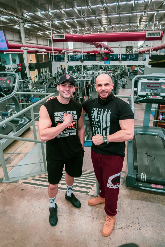 about-us Two men posing and smiling in a well-equipped gym, showcasing fitness camaraderie.
