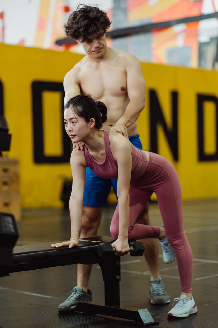 The Art of Drawing Readers In: Your attractive post title goes here A personal trainer guides a woman during an exercise session indoors at a gym.