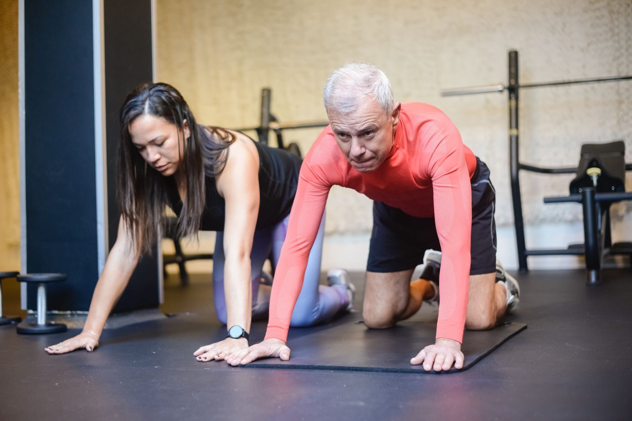 Crafting Captivating Headlines: Your awesome post title goes here Senior man and female trainer performing fitness exercises indoors, promoting healthy aging.